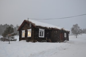Sola skinner i vinduene på gammelstua samtidig som snøbygene feier forbi